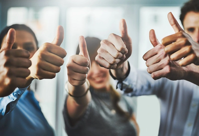 a group of businesspeople showing thumbs up in an office